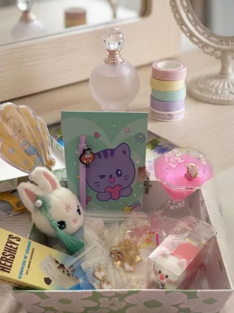 A Rakhi hamper with a cat notebook, pens, a bunny accessory, chocolate and keepsakes in a floral box.