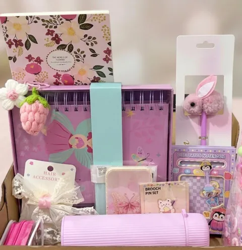 A birthday hamper with colourful notebooks, a bunny pen, a pink flask and hair accessories.